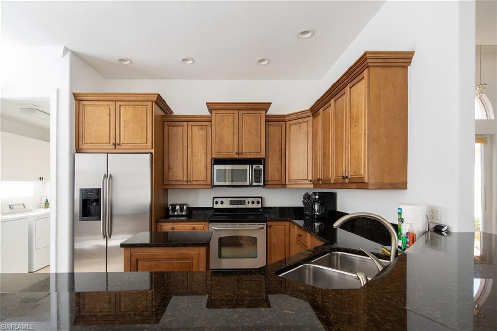 982 Tivoli Court Naples, FL 34104 - Photo 22 of 40 a kitchen with stainless steel appliances granite countertop a refrigerator a stove a sink and white cabinets with wooden floor