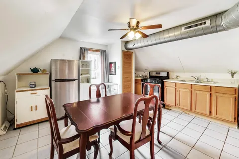 a kitchen with stainless steel appliances granite countertop a dining table chairs refrigerator and cabinets