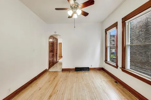 a view of empty room with wooden floor and fan
