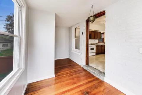 a view of a hallway with wooden floor and a bathroom