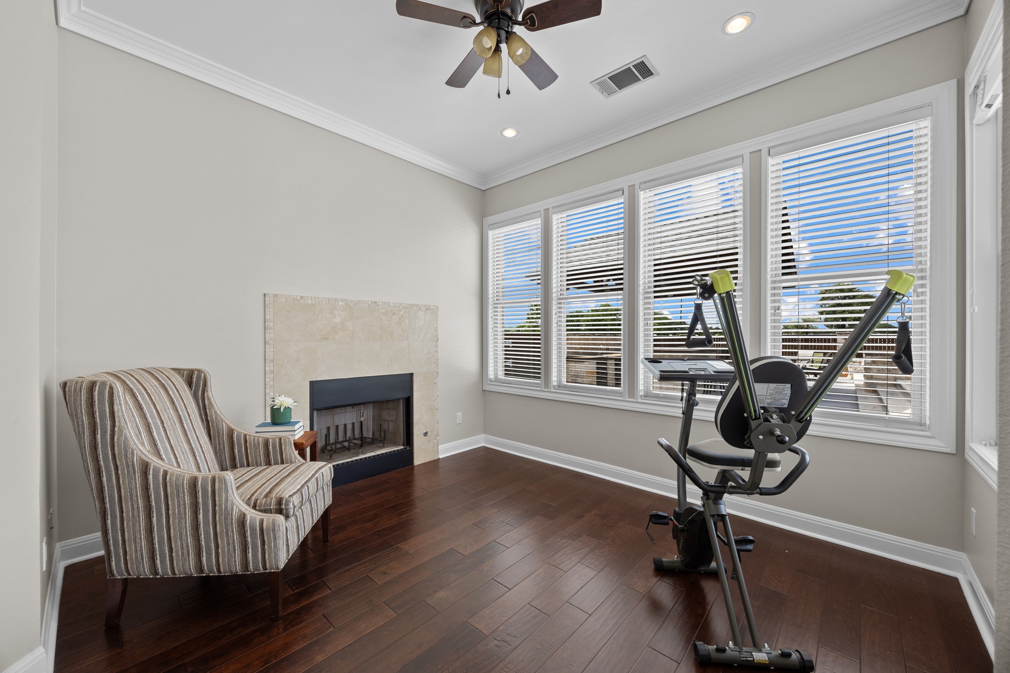 341 Courtnee's Way Georgetown, TX 78626 - Photo 18 of 40 Tucked behind large windows is a versatile bonus space within the suite. Whether you use it as a private gym (as pictured), a sun-drenched reading nook with a tiled fireplace, or a private home office, it offers a peaceful escape with a view.