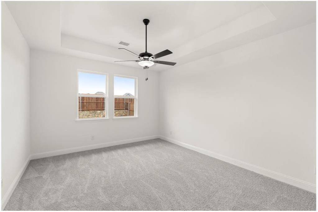 2902 Hanscom Street Forney, TX 75126 - Photo 11 of 28 Empty room with a tray ceiling, light colored carpet, and a ceiling fan