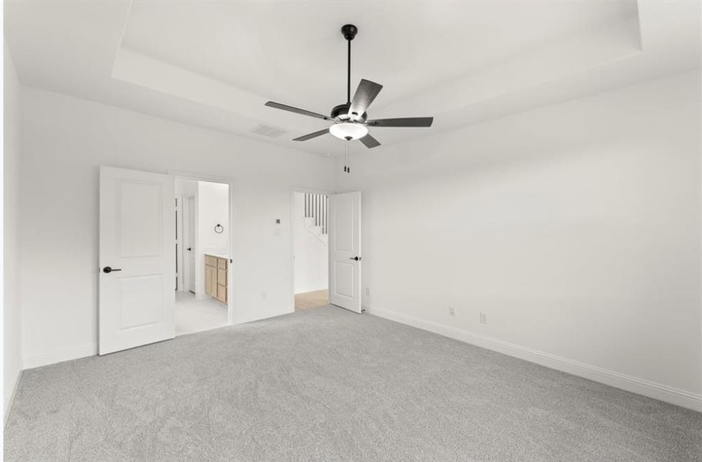 2902 Hanscom Street Forney, TX 75126 - Photo 12 of 28 Unfurnished bedroom featuring a raised ceiling, connected bathroom, light colored carpet, and a ceiling fan