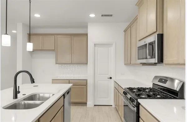 a kitchen with stainless steel appliances a sink a stove and cabinets