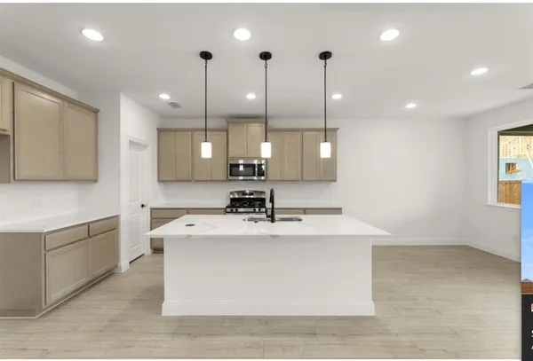 a view of a kitchen with kitchen island a sink stainless steel appliances and cabinets