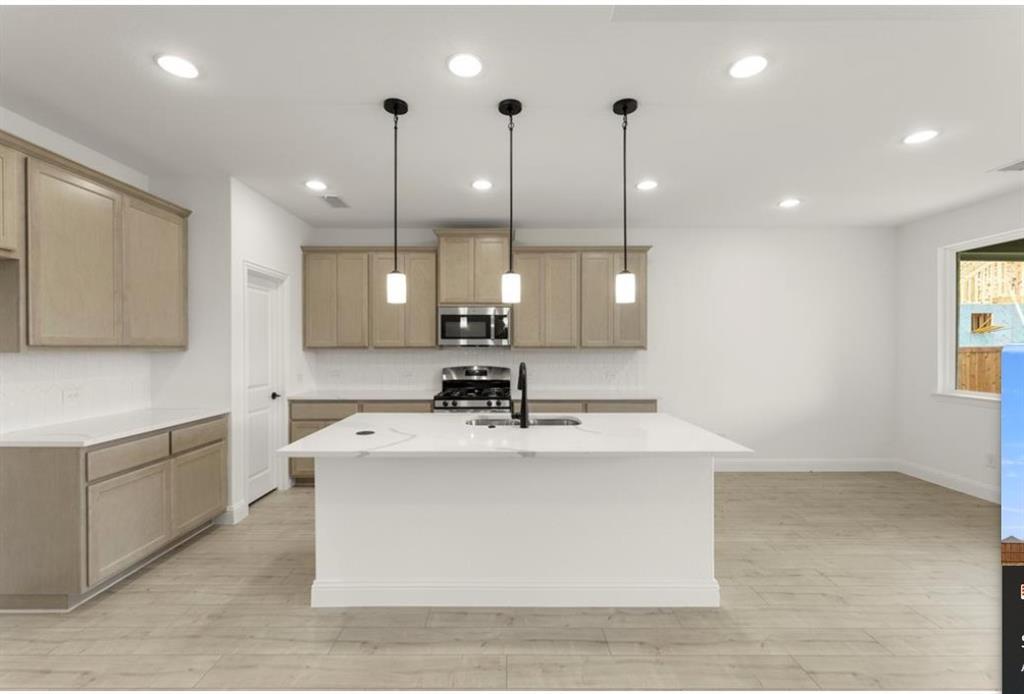 2902 Hanscom Street Forney, TX 75126 - Photo 6 of 28 Kitchen featuring a kitchen island with sink, stainless steel appliances, light wood-style flooring, pendant lighting, and light stone countertops