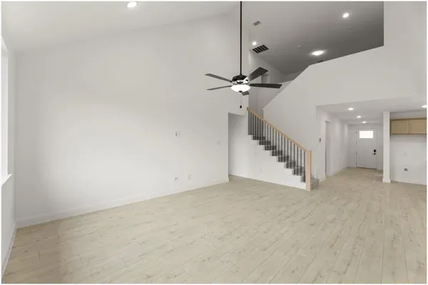 a view of an empty room with a chandelier fan