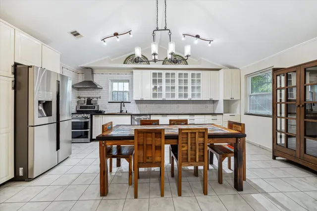 a kitchen with stainless steel appliances granite countertop a stove a refrigerator a sink a dining table and chairs