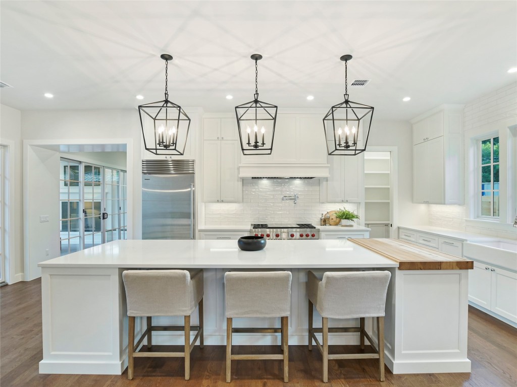 a kitchen with stainless steel appliances kitchen island granite countertop a table chairs in it and white cabinets