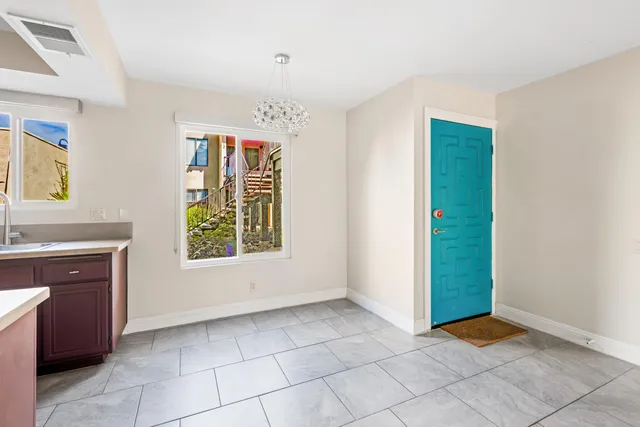a view of an empty room with window and chandelier fan