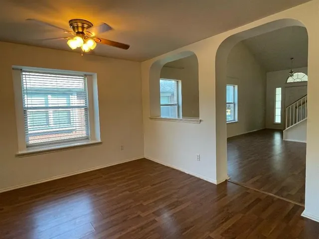 a view of an empty room with window and wooden floor