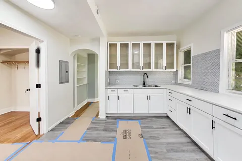 a large white kitchen with granite countertop a sink