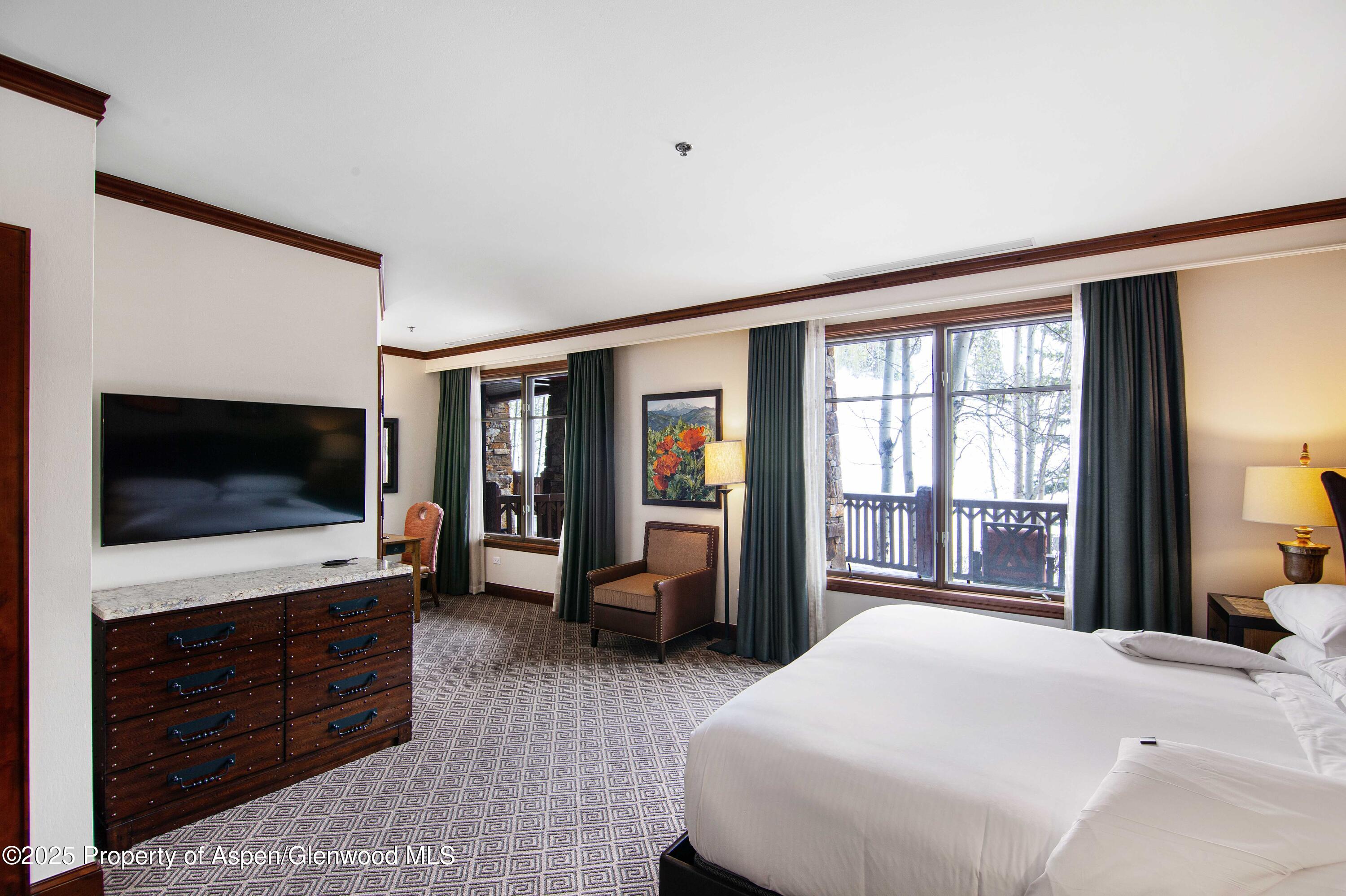 197 Prospector Road, Unit 2307SUMMER 12 Aspen, CO 81611 - Photo 2 of 18 a bedroom with a bed and flat screen tv