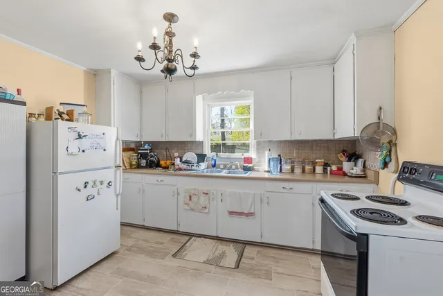 a kitchen with refrigerator a stove a sink and a chandelier