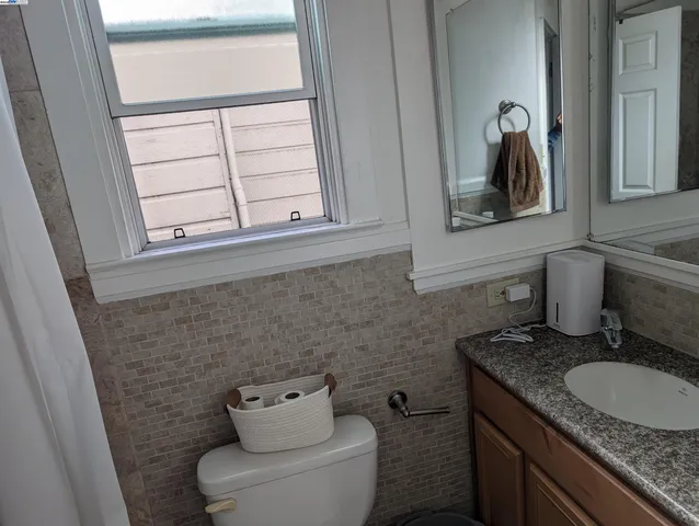 a bathroom with a granite countertop toilet sink and mirror