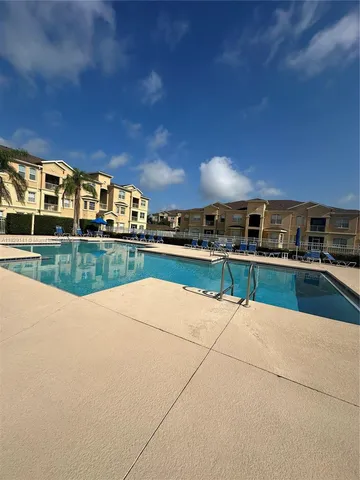 a view of swimming pool with outdoor seating and house in the background