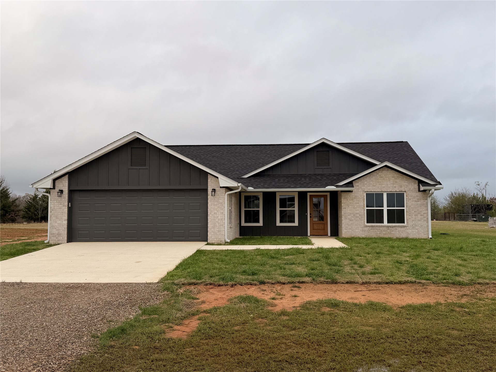 2915 East 2090 Road, Unit LOT 1 Hugo, OK 74743 - Photo 1 of 28 Light-colored brick exterior with dark vertical siding accents