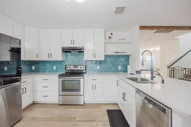 a kitchen with white cabinets appliances and sink