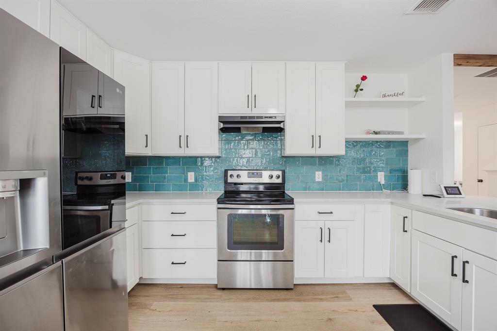 7935 Faithful Trail Dallas, TX 75237 - Photo 18 of 38 Kitchen featuring appliances with stainless steel finishes, white cabinetry, open shelves, and light wood-type flooring