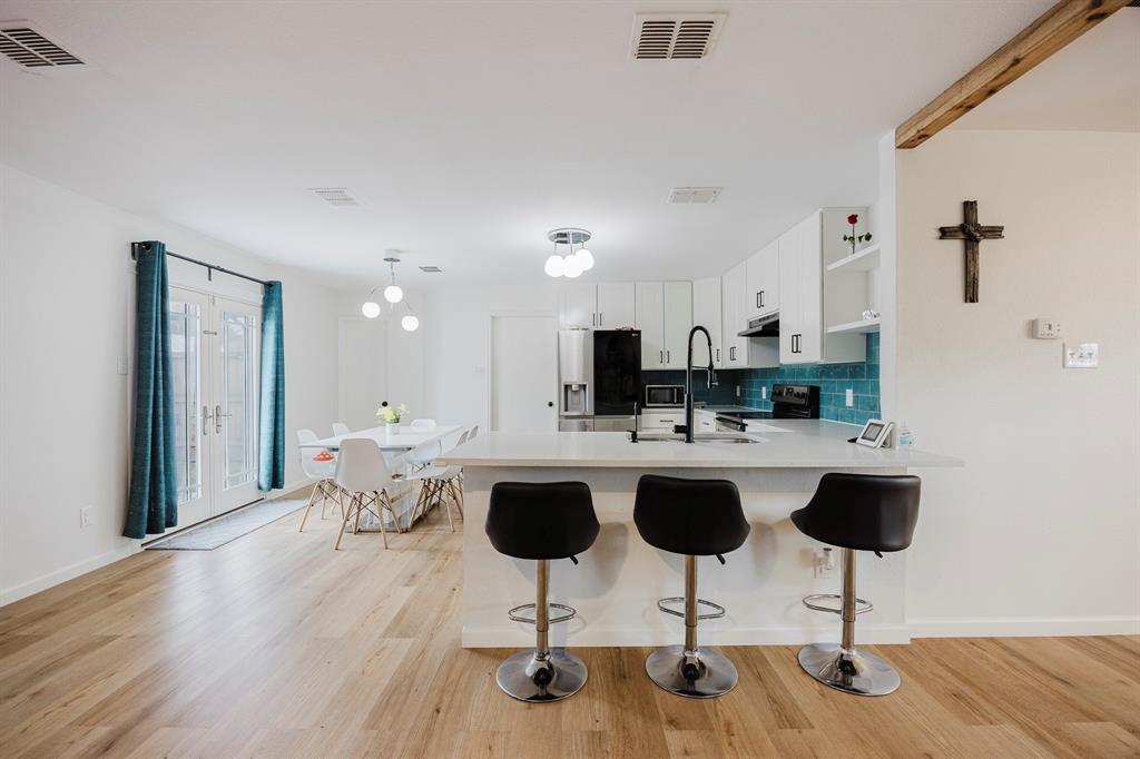 7935 Faithful Trail Dallas, TX 75237 - Photo 8 of 38 Kitchen with a kitchen breakfast bar, a peninsula, white cabinetry, decorative backsplash, and open shelves