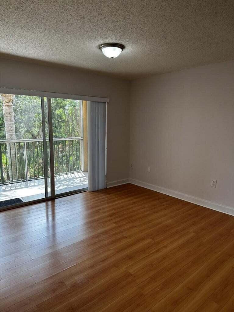 3615 Northwest Adriatic Lane, Unit 204 Jensen Beach, FL 34957 - Photo 11 of 40 a view of an empty room with wooden floor and a window