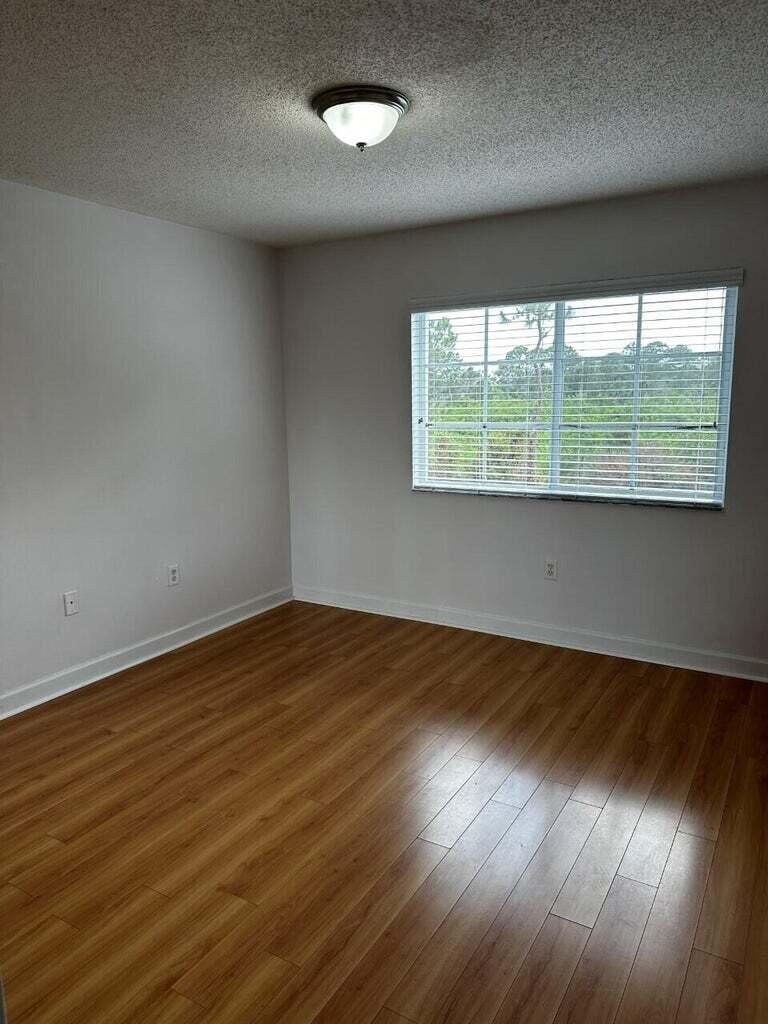 3615 Northwest Adriatic Lane, Unit 204 Jensen Beach, FL 34957 - Photo 19 of 40 an empty room with wooden floor and windows