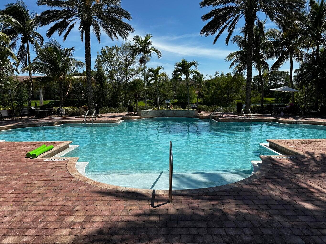 3615 Northwest Adriatic Lane, Unit 204 Jensen Beach, FL 34957 - Photo 27 of 40 a view of a swimming pool with a garden and trees