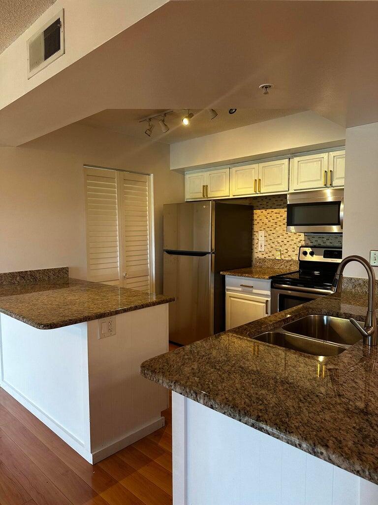 3615 Northwest Adriatic Lane, Unit 204 Jensen Beach, FL 34957 - Photo 9 of 40 a kitchen with stainless steel appliances granite countertop a sink stove and refrigerator