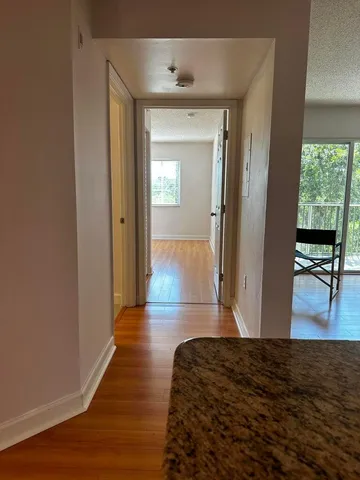 a view of a hallway view with wooden floor and a living room