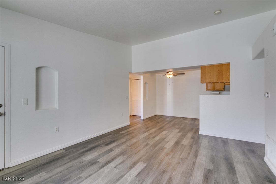 3318 North Decatur Boulevard, Unit 2138 Las Vegas, NV 89130 - Photo 15 of 40 Unfurnished living room featuring wood finished floors, a ceiling fan, and baseboards