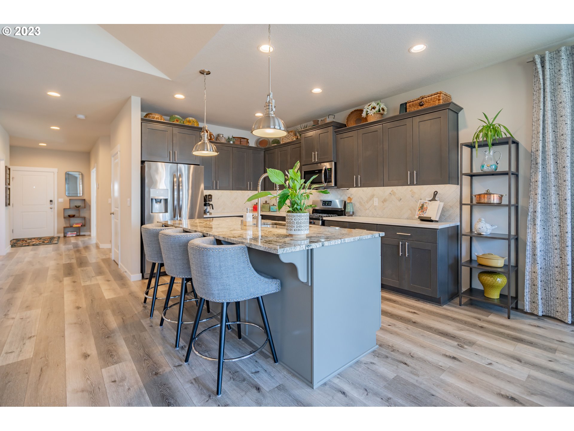 8518 North 1st Street Ridgefield, WA 98642 - Photo 9 of 41 a kitchen with kitchen island stainless steel appliances a dining table chairs sink and wooden floor