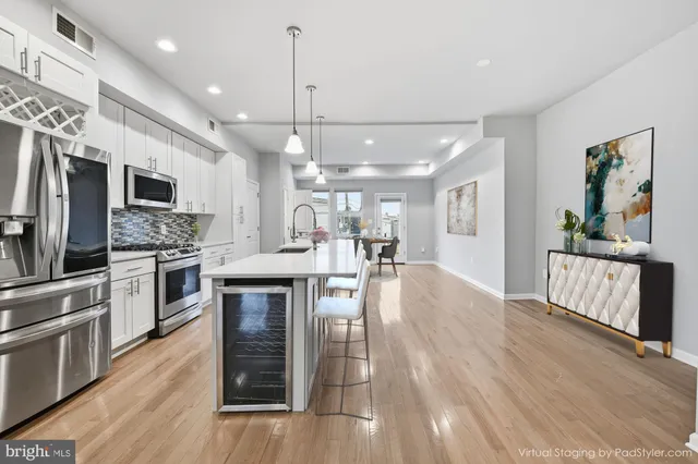 a kitchen with stainless steel appliances kitchen island granite countertop a stove top oven a sink dishwasher a dining table and chairs with wooden floor