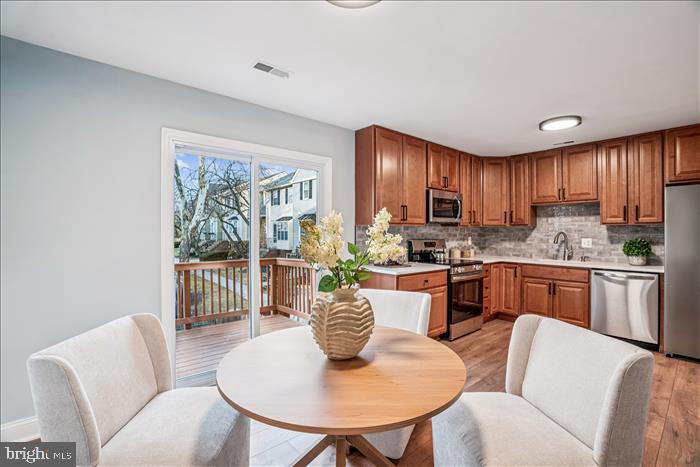 7646 South Arbory Lane, Unit 320 Laurel, MD 20707 - Photo 15 of 45 a kitchen with stainless steel appliances granite countertop a kitchen island a stove a table and chairs with wooden floor