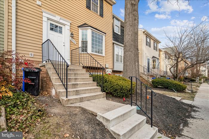 7646 South Arbory Lane, Unit 320 Laurel, MD 20707 - Photo 3 of 45 a view of a house with wooden stairs and a yard with plants and wooden fence
