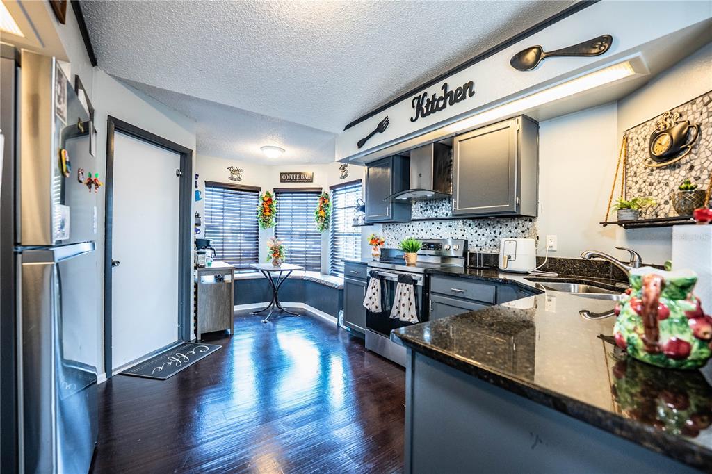 3304 Fox Ridge Drive Winter Haven, FL 33884 - Photo 5 of 60 a kitchen with stainless steel appliances granite countertop a refrigerator a sink dishwasher a stove and a microwave oven with wooden floor