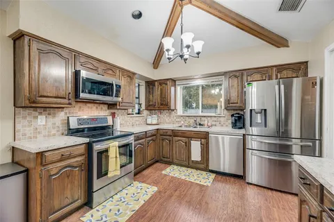 a kitchen with stainless steel appliances granite countertop a refrigerator a stove top oven a sink and dishwasher