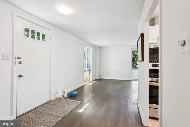 an empty room with wooden floor closet and windows