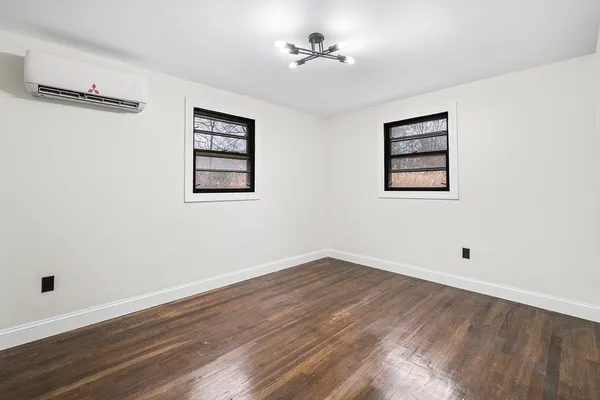 a view of an empty room with wooden floor and a ceiling fan