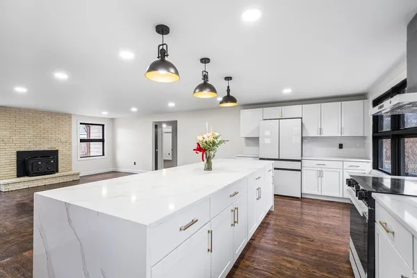 a large white kitchen with a stove a sink dishwasher and a refrigerator with wooden floor