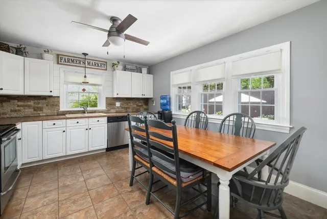 a kitchen with granite countertop a stove a sink a dining table and chairs with white cabinets
