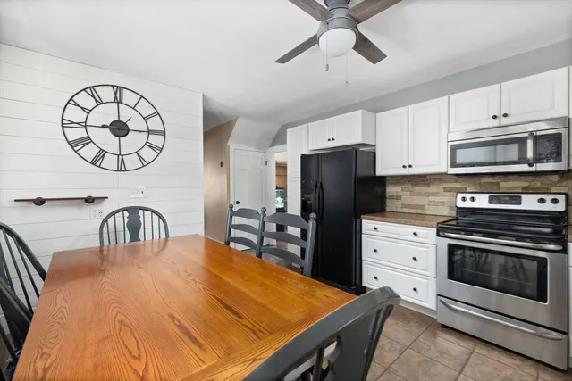 a kitchen with stainless steel appliances granite countertop a stove a refrigerator a sink a microwave with a dining table and chairs