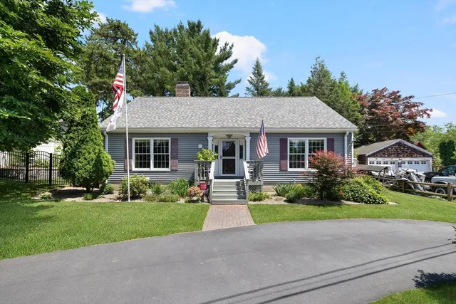a front view of a house with a yard and potted plants