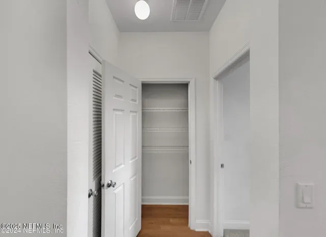 an empty room with chandelier fan and windows