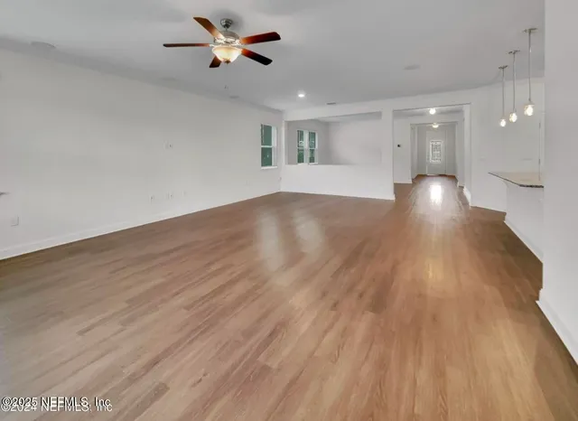 a kitchen with refrigerator a stove a dining table and chairs with wooden floor