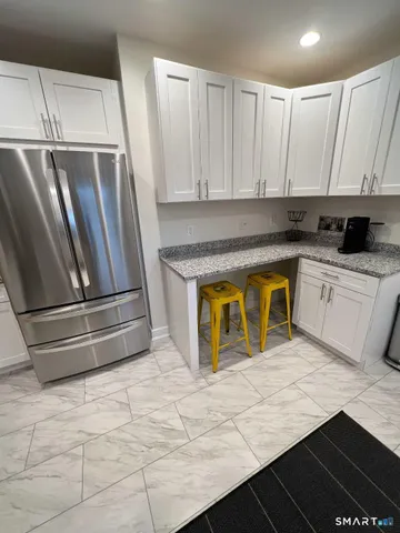 a kitchen with stainless steel appliances granite countertop a refrigerator a stove and white cabinets