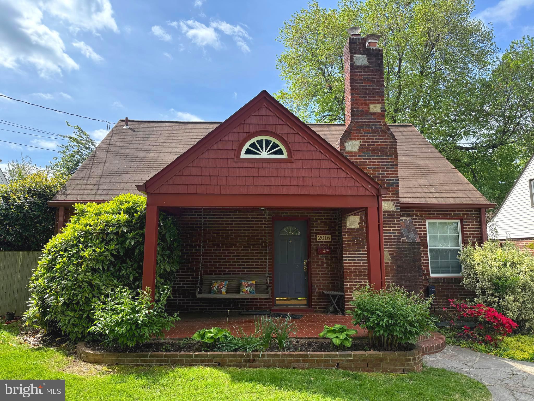 a view of a house with brick walls and a yard with plants