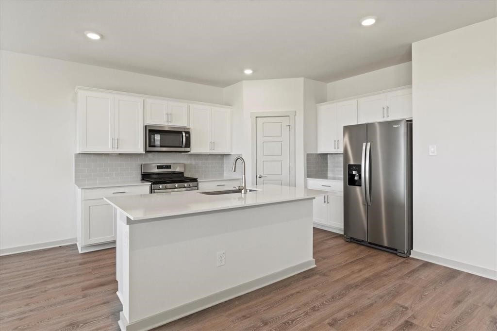 530 Wilshire Road San Marcos, TX 78666 - Photo 6 of 30 a kitchen with a refrigerator a stove top oven a sink and dishwasher with wooden floor