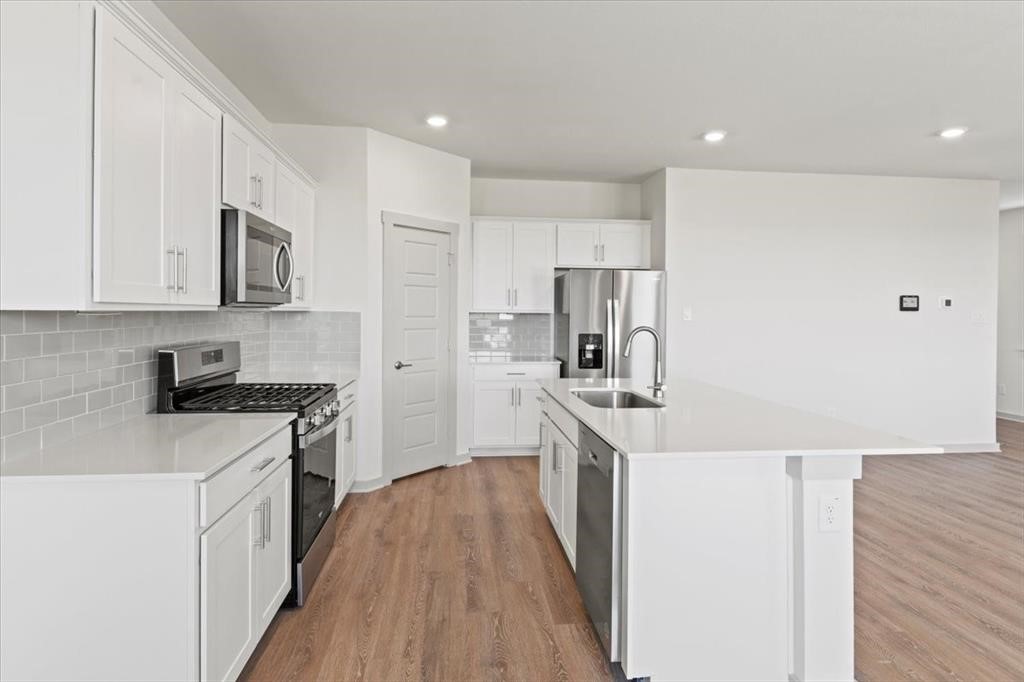530 Wilshire Road San Marcos, TX 78666 - Photo 7 of 30 a kitchen with stainless steel appliances granite countertop a stove top oven a sink a refrigerator white cabinets and wooden floor