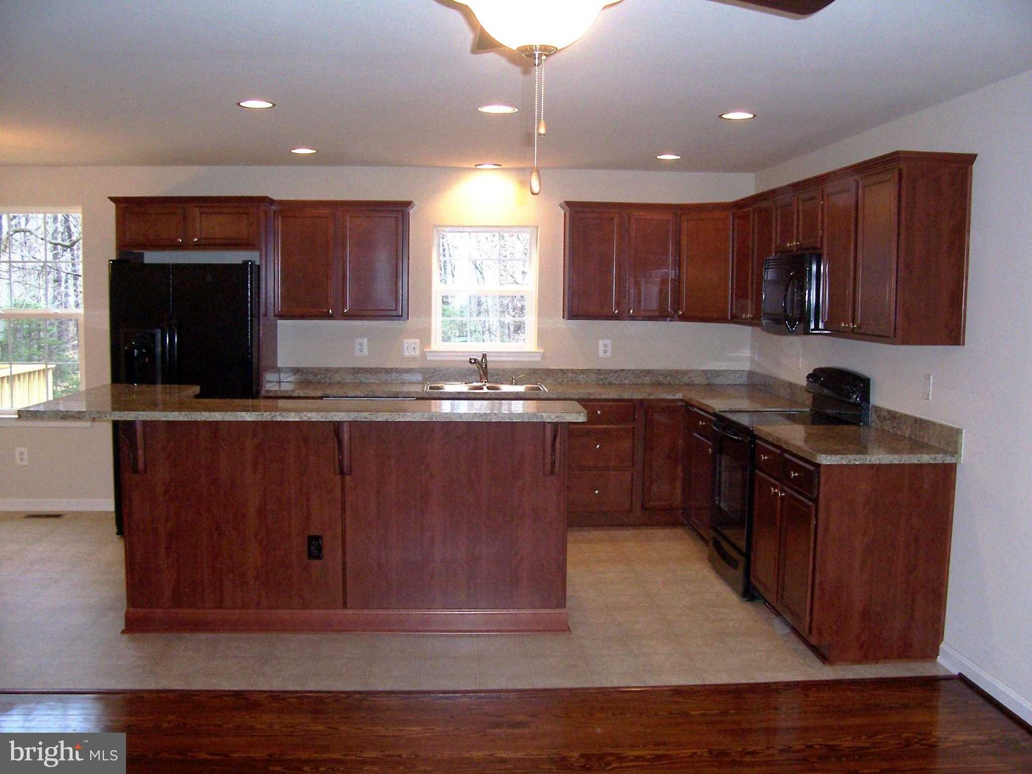 361 Emerson Road Owings, MD 20736 - Photo 7 of 25 a kitchen with kitchen island granite countertop wood cabinets and stainless steel appliances