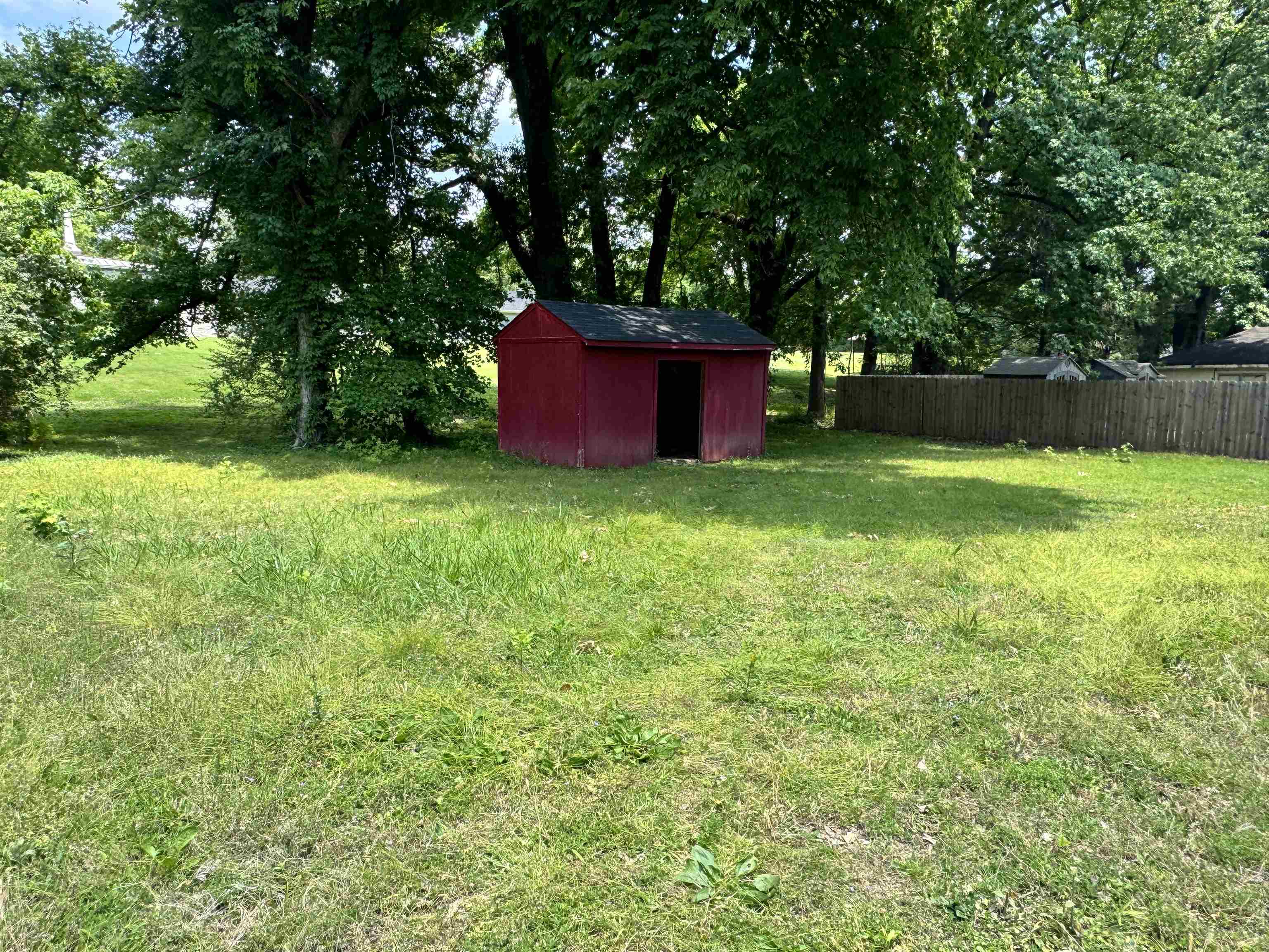 5520 Wagon Rd Gap, Unit GAP Memphis, TN 38134 - Photo 19 of 19 Spacious green area featuring a red utility shed with a dark shingle roof and a wooden fence along the property perimeter